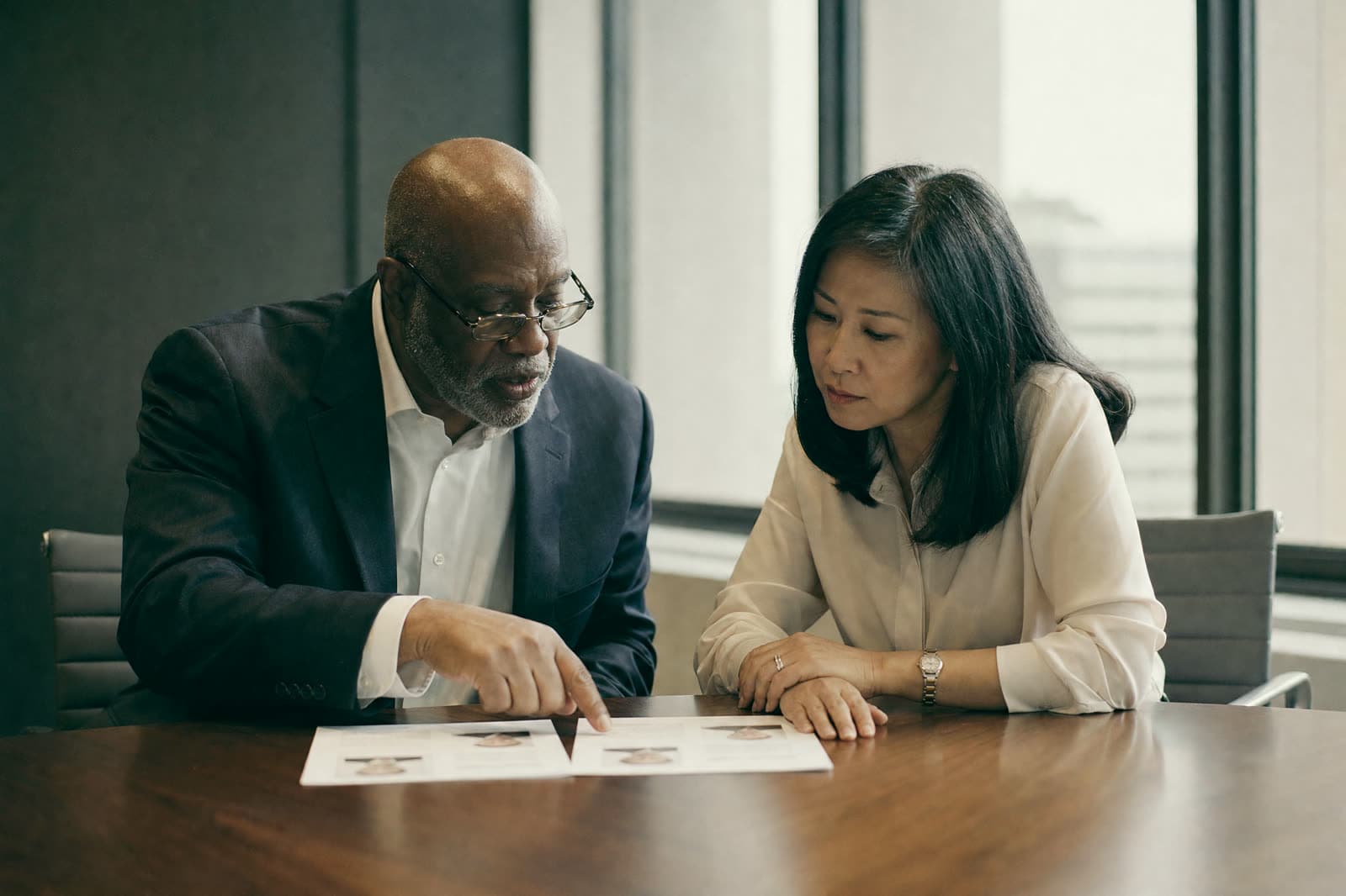 Two healthcare leaders comparing printed candidate profiles side by side